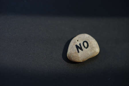 Pebble stone with text NO on black table.の写真素材