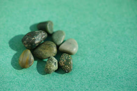 Set of green pebble stones at green sunny table. Copy spaceの写真素材