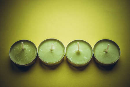 Four low new green candles on lime table.の写真素材