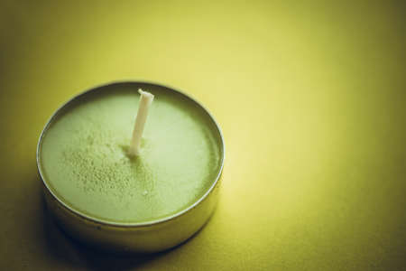 One low new green candle on lime table.