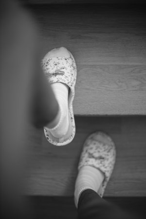 Female feet in socks and slippers are walking up the stairs. BW photoの写真素材