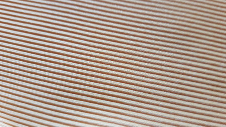 Beige cotton fabric with stripes, pale brown background close up.