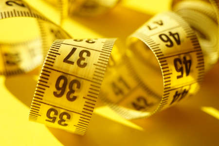 Yellow measuring tape on the sunny table closeup.