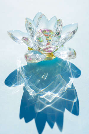 Beautiful crystal lotus flower on a blue sunny table.