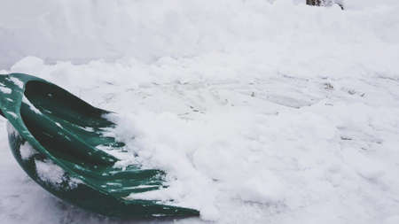 Green snow shovel cleans the sidewalk in winter, side viewの写真素材
