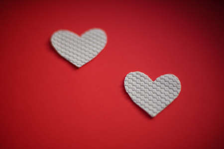 Two white fabric hearts on red table. Valentine's day themeの写真素材