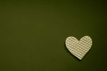 Fabric white heart on dark olive green table. Art card. Copy space