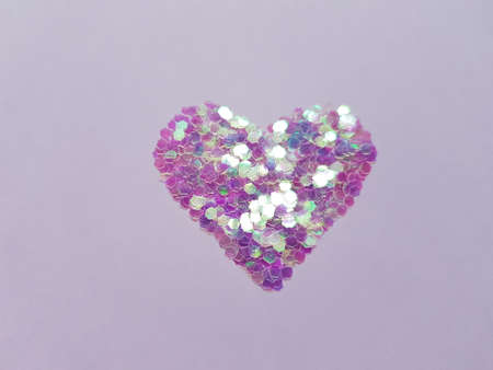 Violet heart made of sequins on a purple table.の写真素材