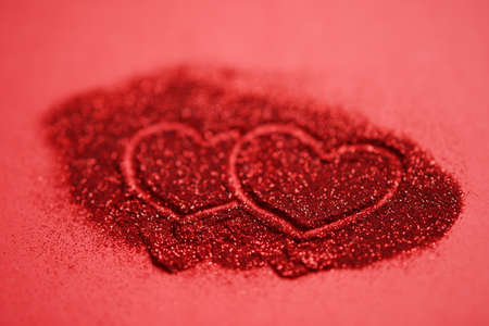Red table with two hearts, finger painted on glitter.の写真素材