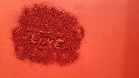 Red table with pile of shiny sparkles and text love. Art card. Copy space