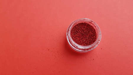 Plastic jar with red glitter on red paper table.の写真素材