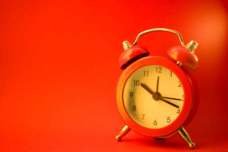 new red round clock on red table, side view, copy space.の写真素材