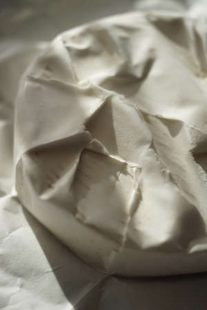 Closeup whole round camembert cheese on a sunny wooden tableの写真素材