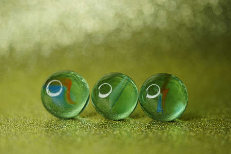 Three glass balls on shiny golden table with blurred background in bubbles.の写真素材