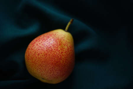 Yellow orange pear on a dark green table.の写真素材