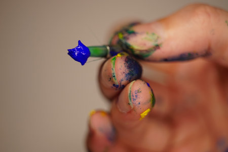 Painted fingers hold with brush and blue paint.の写真素材