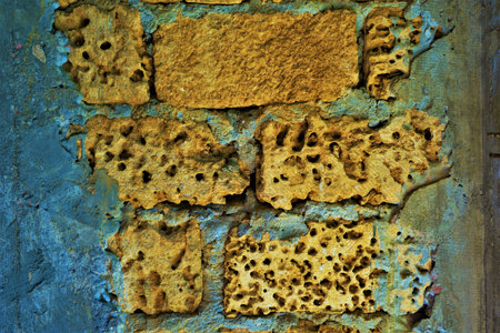 Old yellow wall of limestone with natural holes and gray cement seams, close-up view.の写真素材