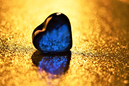 One blue glass herat on golden shiny tableの写真素材