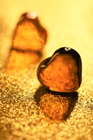 Amber glass hearts on glitter golden tableの写真素材