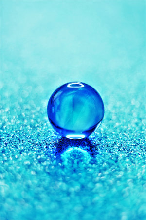 One glass ball on shiny blue table.の写真素材