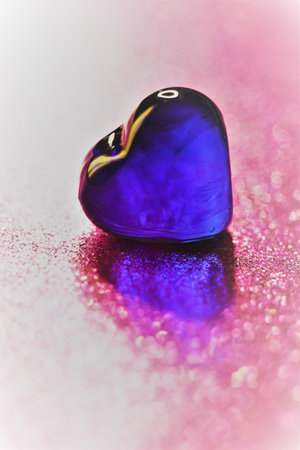 One blue glass herat on glitter shiny pink table. art cardの写真素材