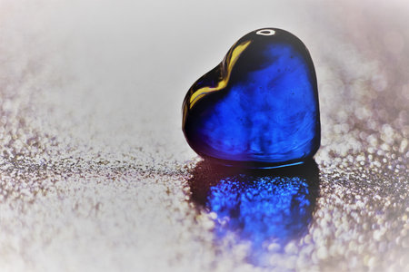 Blue glass heart on shiny silver table. art cardの写真素材