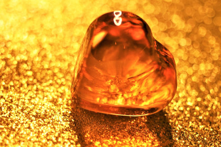 Brown glass heart on shiny golden table.の写真素材