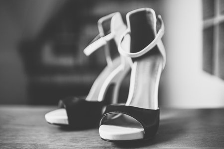 Black and white heeled sandals stand on the wooden floor.の写真素材