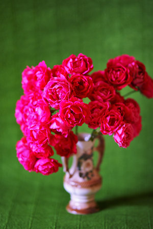 Bouquet of pink roses in a ceramic vase on green background.の写真素材