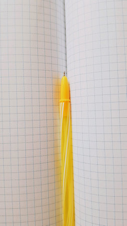 Closeup checkered paper background in blue cage with yellow pen in spread.の写真素材