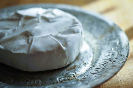 Whole round camembert cheese on a silver plate, side view.の写真素材