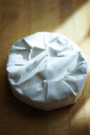 Whole round camembert cheese on a sunny wooden board.の写真素材