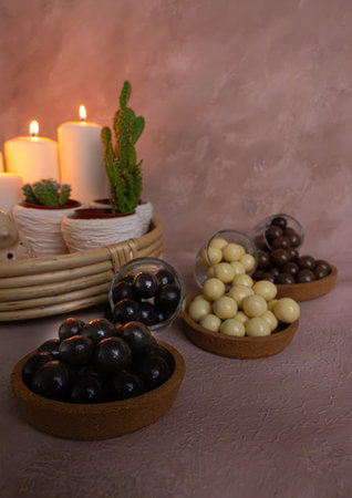 Candles and chocolate balls in a wooden bowl on a brown background