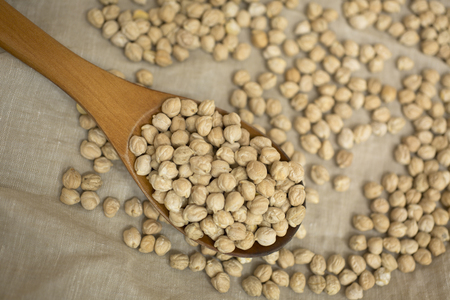uncooked chickpeas in wooden spoon on linenの写真素材