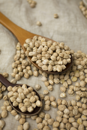 uncooked chickpeas in wooden spoon on linenの写真素材