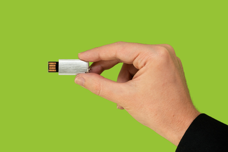 Flash memory on hand with isolated green backgroundの写真素材