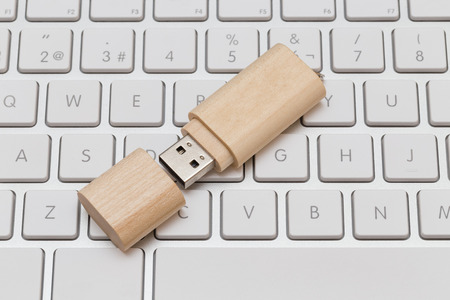 USB flash drive wooden on white keyboardの写真素材