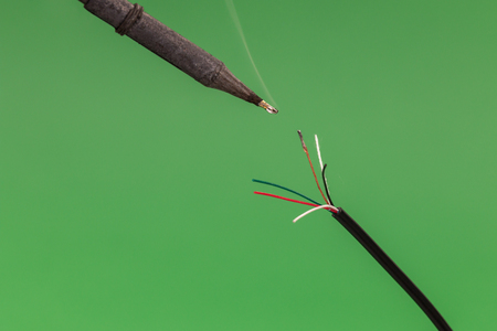 Soldering a copper wire on green background. Front viewの写真素材