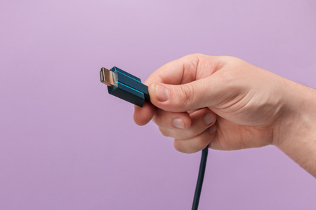 Hand holding HDMI cable. In purple backgroundの写真素材