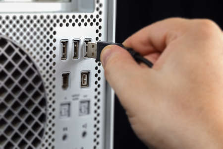 Hand connecting USB to the computer. Seen from near
