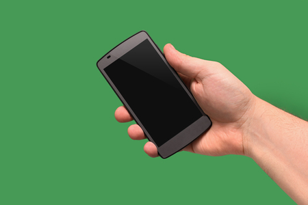 Mobile phone in hand. On green backgroundの写真素材