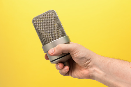 Mic, professional microphone in hand. yellow background
