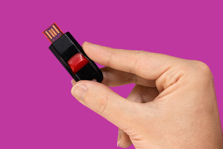 Black and red USB flash memory in hand. Pink backgroundの写真素材
