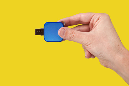 Blue USB flash memory in hand. Yellow background