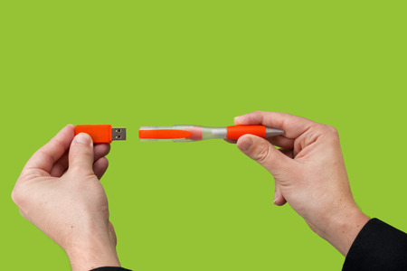 USB orange flash drive in hand. Green backgroundの写真素材