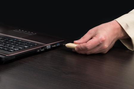 USB flash memory by hand connecting to a laptop. Front viewの写真素材