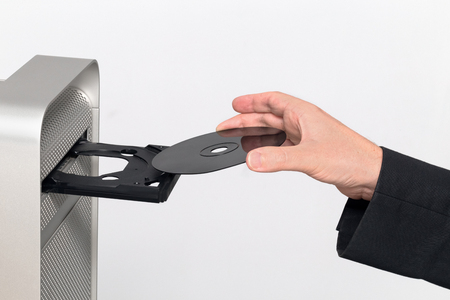 Inserting a black CD / DVD into a computer. Hand insert. On white backgroundの写真素材