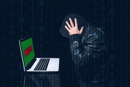 Anonymous hacked putting his hands on his head with much concern. Dark background and binary 0 and 1