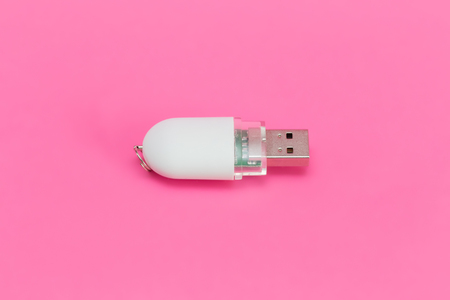 White USB flash drive on a pink background. Top view