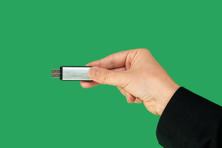 Metal pen drive on hand with isolated green background. Front viewの写真素材